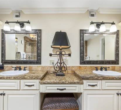 Pamper yourself at this elegant double vanity with granite countertops, ornate mirrors, and charming built-in seating area for your morning routine.