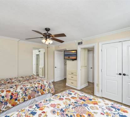 Rest peacefully in your bright bedroom featuring twin beds with cheerful floral linens, ceiling fan, and ample storage space.