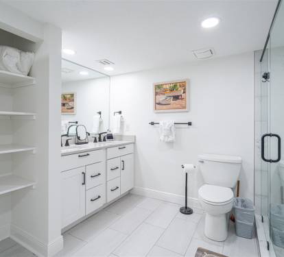 Step into your pristine private bathroom with spacious glass shower, elegant vanity, and thoughtful built-in shelving for all essentials.