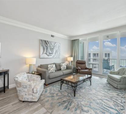 Relax in your bright coastal living room with ocean views through floor-to-ceiling windows and comfortable seating for your group.
