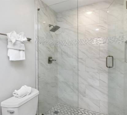 Step into your luxurious marble-clad shower with rainfall head and mosaic accents. Fresh towels await nearby.