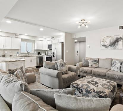 Sink into plush gray seating while your group gathers in this bright open-concept space connecting kitchen and living areas.