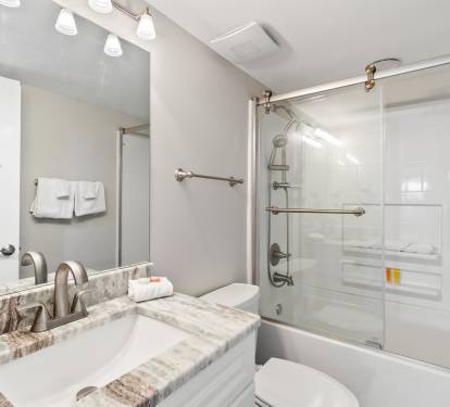 Unwind in your sleek bathroom featuring marble counters, modern fixtures, and a refreshing shower-tub combo after exploring the city.