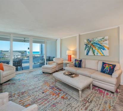 Unwind in your elegant living room where coastal artwork and vibrant rugs create a tropical paradise, while stunning balcony views invite relaxation.