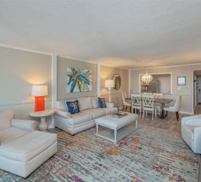 Sink into plush sofas and unwind in your spacious living room, where coastal artwork and pops of coral create a serene retreat.