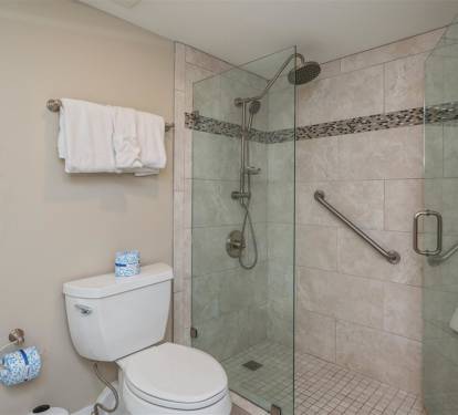 Step into your private spa-like bathroom featuring a spacious glass-enclosed shower with rainfall head and thoughtful accessibility features for ultimate comfort.