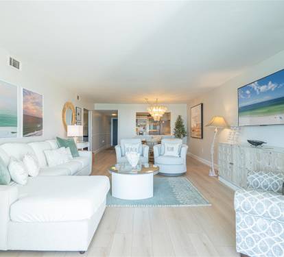 Sink into plush coastal comfort with soft sea-green accents and beach artwork surrounding you in this serene living space.