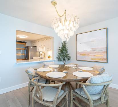 Gather around your elegant dining table under soft chandelier light, with the modern kitchen just steps away for easy entertaining.