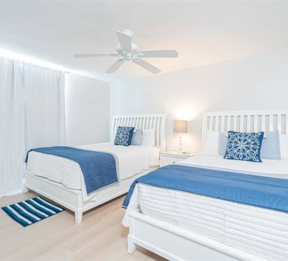 Unwind in your coastal-inspired twin bedroom, where crisp white linens meet ocean-blue accents for a peaceful night's rest.