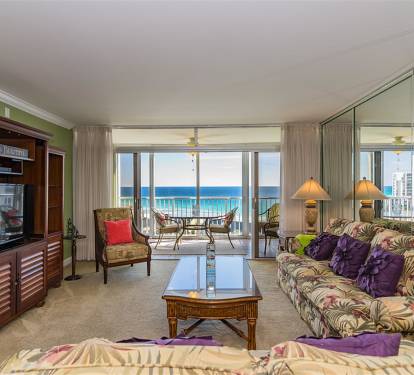 Relax in your bright living room with tropical decor and stunning ocean views through floor-to-ceiling windows opening to your private balcony.