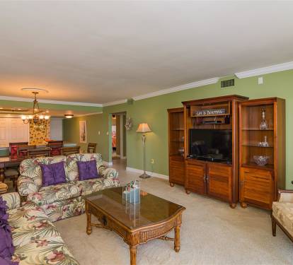 Unwind in your spacious living room featuring tropical-inspired seating, entertainment center, and soothing green walls that create the perfect retreat atmosphere.