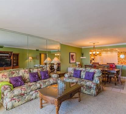 Relax in your tropical-themed living space with vibrant furnishings and open dining area perfect for memorable vacation meals.