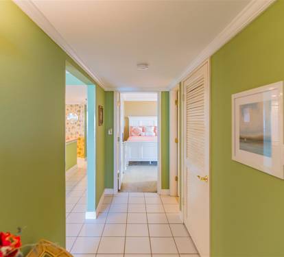 Bright hallway connects your space with cheerful green walls, tropical art, and fresh flowers creating a welcoming tropical atmosphere throughout your stay.