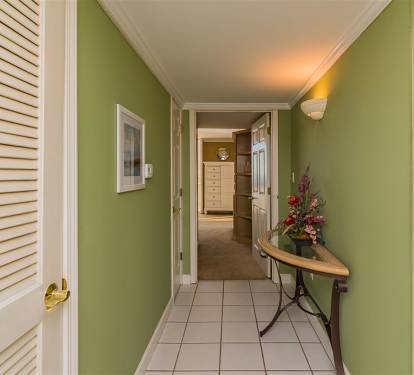 Step into your welcoming hallway where soothing green walls and warm lighting create an inviting path to your comfortable rooms.