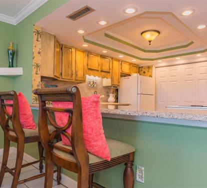 Your bright kitchen invites culinary adventures with granite counters, warm wood cabinets, and tropical charm.