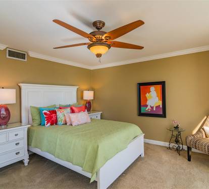 Unwind in your cozy bedroom with warm golden walls, fresh green linens, and tropical decor that creates the perfect retreat after busy days.