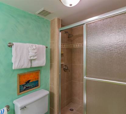 Your vibrant bathroom features calming turquoise walls and a spacious walk-in shower with elegant tiled walls, perfect for refreshing after beach days.