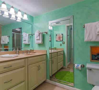 Your vibrant aqua bathroom features dual vanities, modern lighting, and coastal artwork that creates a refreshing seaside retreat atmosphere.