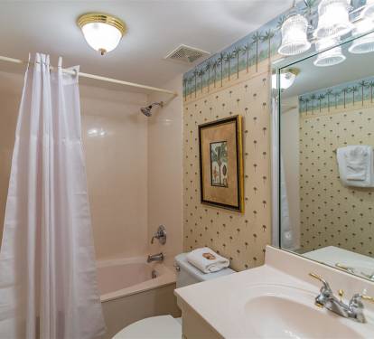 Step into your charming bathroom with tropical wallpaper and warm lighting that creates a cozy retreat for unwinding.