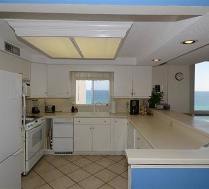 Cook with breathtaking ocean views streaming through your kitchen window, where white cabinets and warm lighting create the perfect coastal retreat.