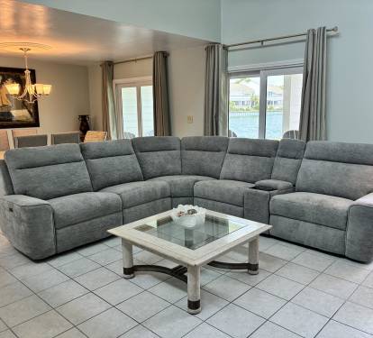 Sink into your spacious sectional sofa and unwind while enjoying stunning water views through floor-to-ceiling windows in this elegant living space.