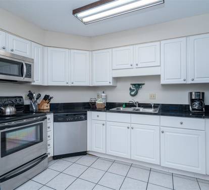 Your fully equipped kitchen features crisp white cabinets, granite countertops, and stainless steel appliances, perfect for preparing family meals during your stay.