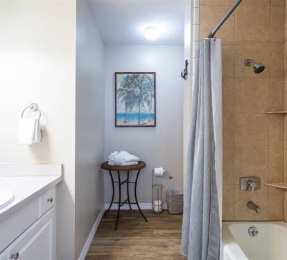Unwind in your spa-like bathroom with a deep soaking tub, rainfall shower, and coastal artwork creating tranquil vibes.