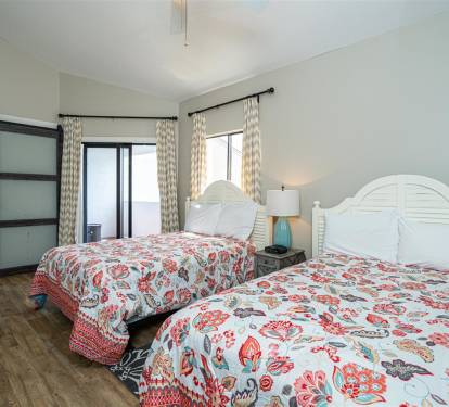 Sink into comfort with two plush beds adorned in vibrant floral linens, where natural light streams through elegant curtains.