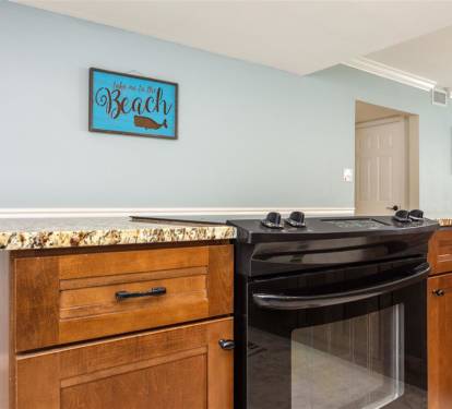 Your beach-themed kitchen awaits with granite countertops, warm wood cabinets, and a modern gas range ready for your culinary adventures.