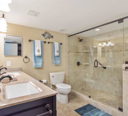 Your luxurious bathroom features a spacious glass-enclosed shower, elegant granite countertops, and soothing coastal touches that make every moment feel like a spa retreat.