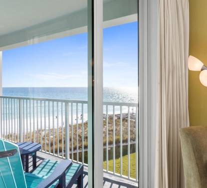 Your private balcony opens to breathtaking ocean views where turquoise chairs await your morning coffee moments.