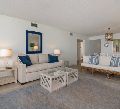 Relax in this spacious living room featuring plush seating, coastal blue accents, and elegant lighting that creates your perfect seaside retreat.