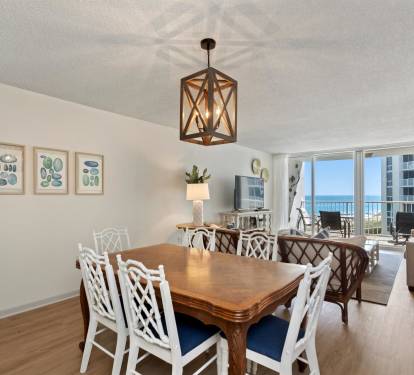 Gather around your elegant dining table while soaking in stunning ocean views through floor-to-ceiling windows in this beautifully appointed space.