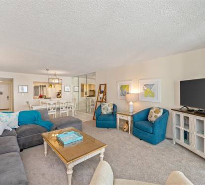 Sink into plush sofas and vibrant blue chairs while coastal artwork and soft lighting create your perfect retreat atmosphere.