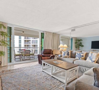 Sink into your spacious living room with plush seating, coastal decor, and balcony views that invite you to relax and unwind.