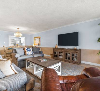 Unwind in your spacious living room with plush seating, smart TV, and elegant chandelier lighting for cozy evenings together.
