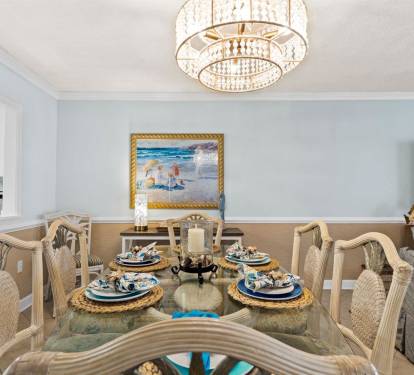Your elegant dining room features a crystal chandelier, coastal artwork, and beautifully set table where you'll create memorable meals together.