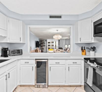 Your fully-equipped kitchen features pristine white cabinets, stainless steel appliances, and a unique pass-through window connecting you to the dining area.