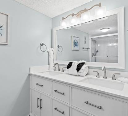 Your spacious dual-sink vanity features elegant coastal artwork and fresh towels, creating a serene morning routine space.