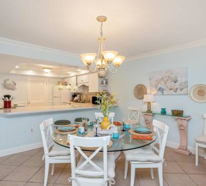 Gather around this elegant glass dining table for memorable meals together, surrounded by coastal charm and open kitchen convenience.