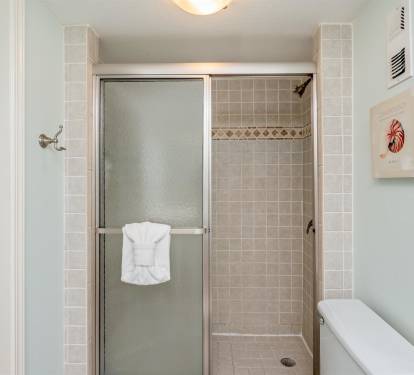 Step into your pristine tiled shower with elegant decorative borders and fresh towels waiting for your arrival.