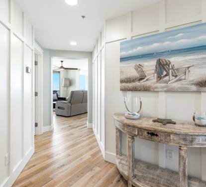 Warm coastal vibes welcome you home through this bright hallway, where beach-themed artwork and rustic furnishings create your perfect seaside retreat.