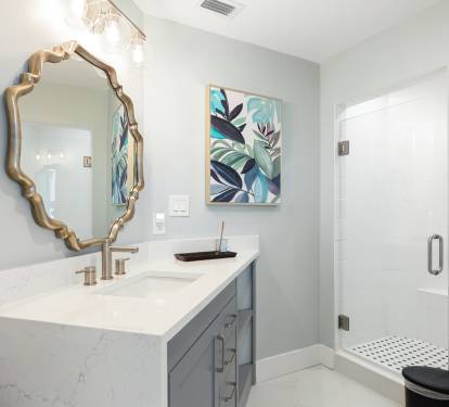 Your elegant bathroom features a spa-like shower, stylish vanity with gold fixtures, and beautiful botanical artwork for a refreshing retreat.