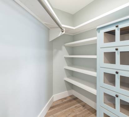 Your private walk-in pantry offers organized storage with built-in shelving and glass-front cabinets for all your culinary essentials.