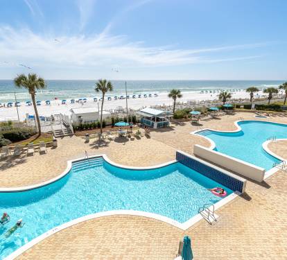 Stunning beachfront resort with expansive pool complex featuring connecting pools, waterfront dining, and direct beach access with pristine white sand.