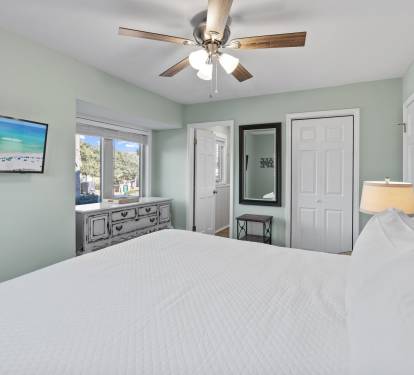 Comfortable primary bedroom with a king-size bed, coastal-inspired décor, and a peaceful atmosphere perfect for relaxing after a fun-filled day at the beach.