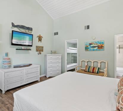 Second-floor guest bedroom featuring a king-size bed, coastal décor, vaulted ceilings, and a relaxing atmosphere perfect for family and friends to unwind after the beach.