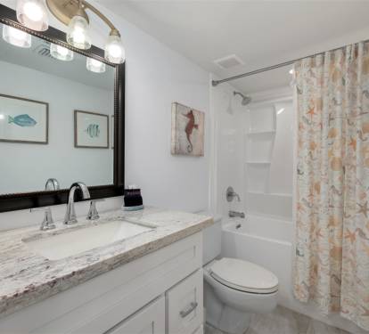 Step into your coastal-themed bathroom with marble counters, nautical artwork, and a relaxing tub-shower combo perfect for unwinding.