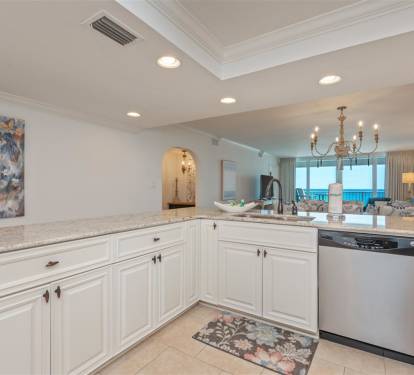 Your elegant white kitchen features granite countertops and stainless appliances, with stunning ocean views through the open living space.
