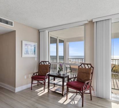 Your comfortable seating area bathes in sunlight with stunning ocean views through floor-to-ceiling windows, perfect for morning coffee or evening relaxation.